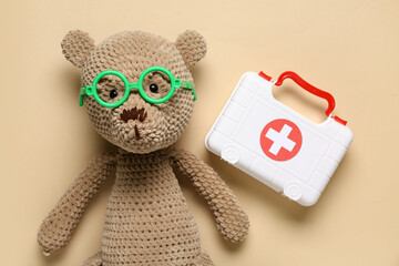 Poster - Toy first aid kit with teddy bear on beige background. Top view