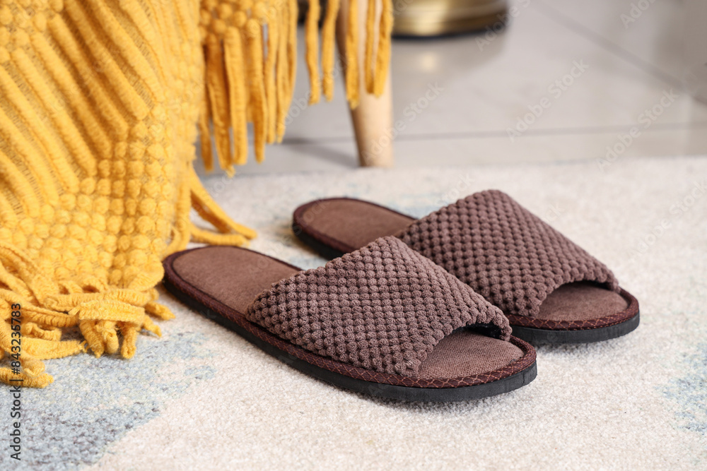 Pair of male slippers on carpet and plaid