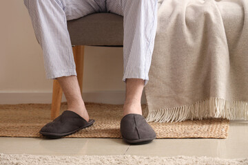 Man in slippers sitting on soft bench with plaid