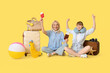 © Pixel-Shot - Mother and daughter sitting on floor with luggage, passport and tickets on yellow background. Travel concept