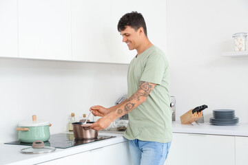 Canvas Print - Young man cooking on stove in kitchen