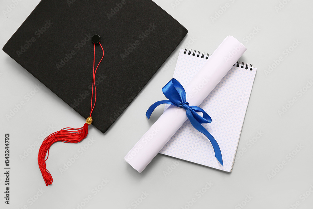 Diploma with blue ribbon, opened book and graduation hat on white background
