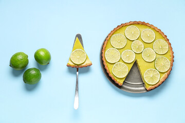 Wall Mural - Plate and spatula with tasty lime tart on blue background