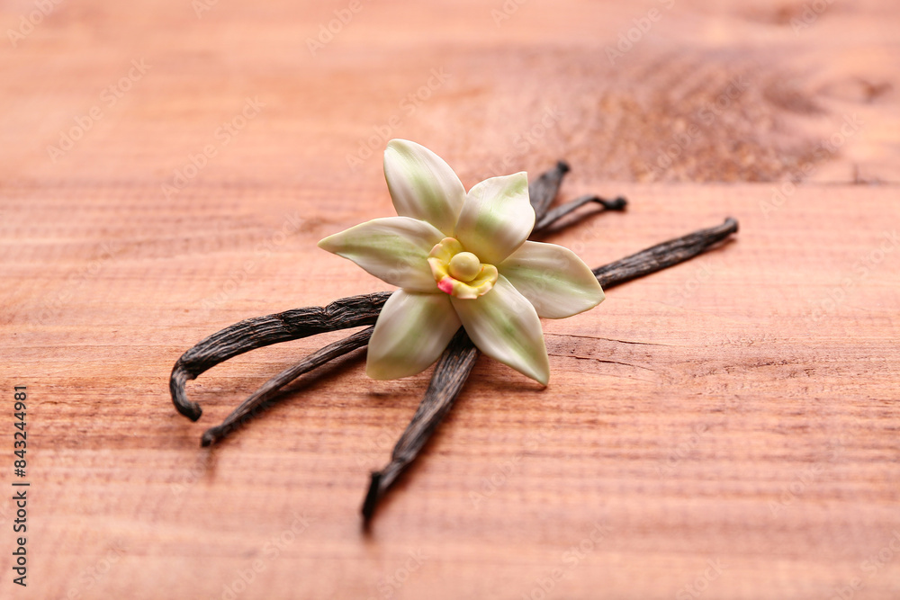 Beautiful vanilla flower and sticks on wooden background