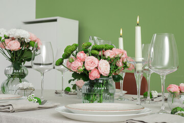 Wall Mural - Table served for wedding celebration with candles and flowers near green wall in dining room