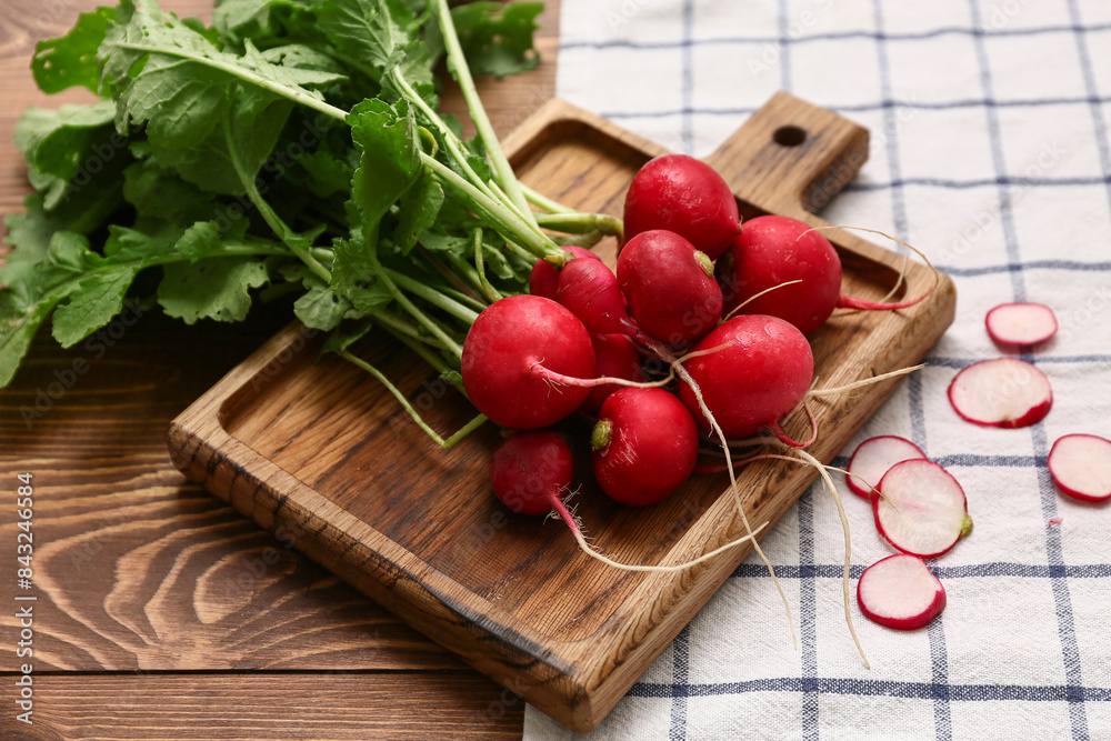 Board with fresh radishes on wooden background, closeup