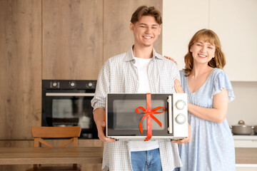 Sticker - Young couple with gift microwave oven in kitchen