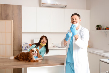 Poster - Veterinarians with vaccine and cute dog on table in clinic