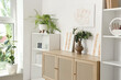 © Pixel-Shot - Vase with eucalyptus and stylish paintings on commode in living room