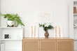 © Pixel-Shot - Vase with eucalyptus and stylish paintings on commode in living room