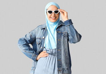 Poster - Stylish Muslim woman in sunglasses on light background