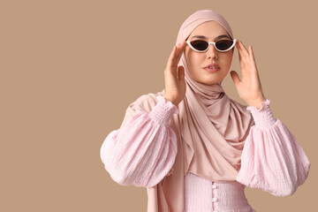 Wall Mural - Stylish Muslim woman in sunglasses on beige background