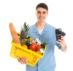 Sticker - Young man with credit card, payment terminal and full shopping basket on white background