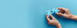 © jex - Two hands of business people connecting puzzle pieces on a blue background with copy space, symbolizing collaboration and teamwork. Background for business solutions, success, and strategy.