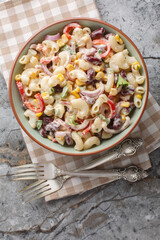 Canvas Print - Southwestern elbow pasta salad with grilled corn, onion, beans, peppers with creamy dressing closeup on the bowl on the table. Vertical top view from above