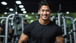 © SKOPUS DRON - Portrait of a young, muscular Asian man wearing a black t-shirt in a gym. Training services, fitness coaching, gym employee staff, body wellness, physical well-being, active lifestyle.