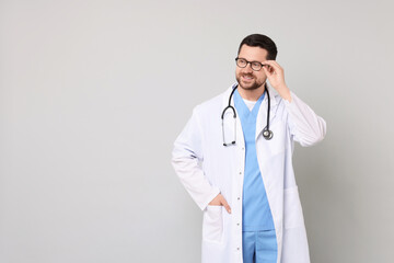 Canvas Print - Portrait of smiling doctor on light grey background. Space for text