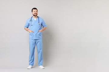 Canvas Print - Full length portrait of smiling doctor on light grey background. Space for text