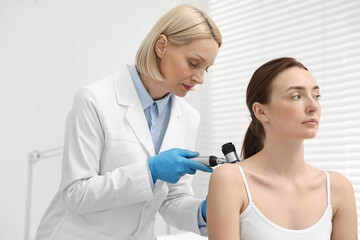 Wall Mural - Dermatologist with dermatoscope examining patient in clinic