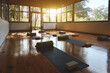 © insta_photos - Empty clean gym wellness center interior with big windows for group retreats sessions in natural forest garden area. Modern studio for yoga meditation practices background with mats on wooden floor.