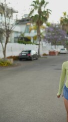 Wall Mural - Young woman running on a treelined street with headphones, exercising among flowers and greenery