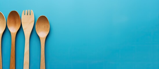 Poster - A bright blue backdrop showcases eco friendly wooden disposable cutlery offering a modern and ecological touch for food banners Ideal for a plastic free copy space image