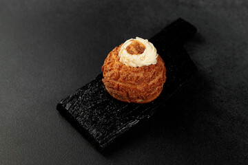 Poster - Classic Shu cake (choux). Custard dough based on butter and milk, classic custard filling with added cream on a black cutting board