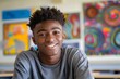 © James - African American teenage boy sitting at his desk in a middle school classroom, smiling and looking directly into the camera. The room is filled with colorful decorations on the wall behind him.