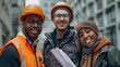 © ifoto - Portrait of smiling males and female construction worker in a Webbfield, holding blueprints while standing against an office building in the city