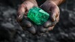 © Zhanna - man's hands hold an emerald gemstone. mining of precious metals