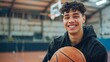 © Anastasiia - Smiling young man holding a basketball in an indoor court. Sports and youth concept.