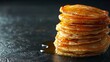 © familymedia - A close-up image of a tall stack of golden-brown pancakes with maple syrup dripping down the sides on a dark surface