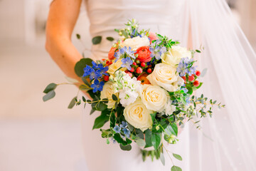 Wall Mural - A bride holds her wedding bouquet, which is an assortment of different roses and colors.