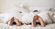 © EmilLL/peopleimages.com - Couple, mattress and feet bedroom for love with duvet in house, peace and morning rest together on holiday. Barefoot people, sleeping and comfort in bed, care and romance under blanket at home