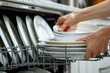 © Ilia K - Close-up of hands loading dishes into a dishwasher