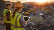 © pier - construction engineers inspecting mining site at sunset with digital tablets for project management