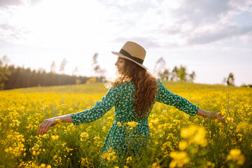 Wall Mural - Happy woman walking in flowering field. Fashion, beauty concept. Summer landscape.