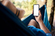 © baranq - Mockup closeup of man using smartphone in hammock