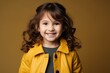 © Stocknterias - Portrait of a cute little girl in yellow jacket over brown background
