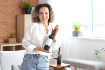 Wall Mural - beautiful middle-aged woman with bottle of wine at home