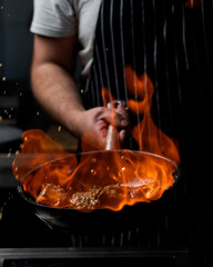 Wok pan cooking asian food with fire flames and flaming meat and vegetables. Hotel professional service food photo concept. Cooking recipe by chef menu.