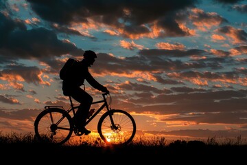 Wall Mural - A person rides a bike against the backdrop of a beautiful sunset, with warm colors and long shadows