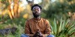 © RealPeopleStudio - A african man meditating in a quiet outdoor setting, focusing on mental well-being and stress reduction