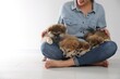© New Africa - Woman with Akita Inu puppies sitting on floor near light wall, closeup. Space for text