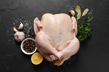 Wall Mural - Fresh raw chicken with spices and lemon on black textured table, flat lay