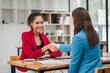 © Satori Studio - Two professional businesswomen shaking hands in a modern office, symbolizing successful collaboration and partnership.