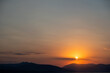 © Rawf8 - Sunset over mountain silhouette on colorful sky background. Golden sun hides behind cloud. Space