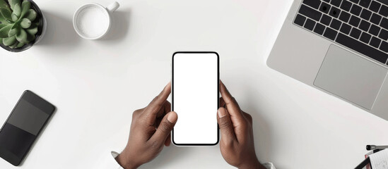 Poster - A person is holding a cell phone on a table with a laptop and a cup