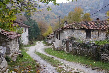 Poster - Cozy alley in a village featuring traditional stone houses and a winding path framed by autumn hues