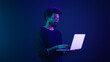 © Yuliia - Arabian Indian man guy male programmer coder internet computer developer businessman business guy gamer hold laptop computer invite come here welcome nod head invitation work in violet neon background